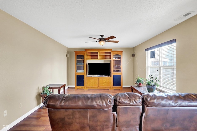 living room featuring a textured ceiling, dark hardwood / wood-style floors, and ceiling fan