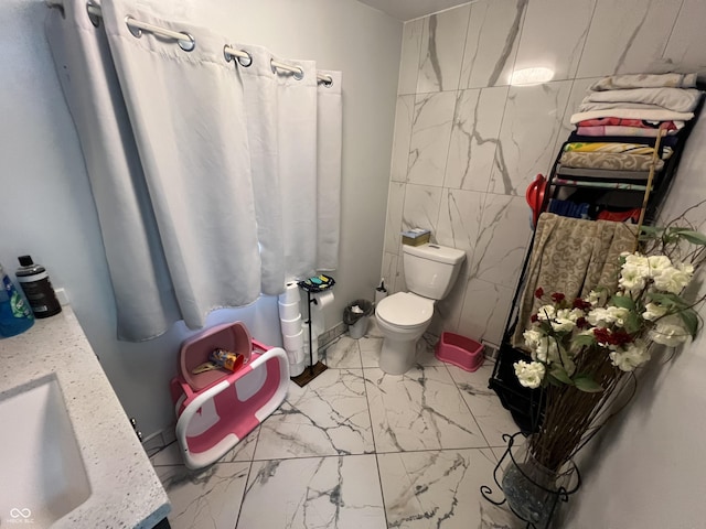 bathroom with vanity, tile walls, and toilet