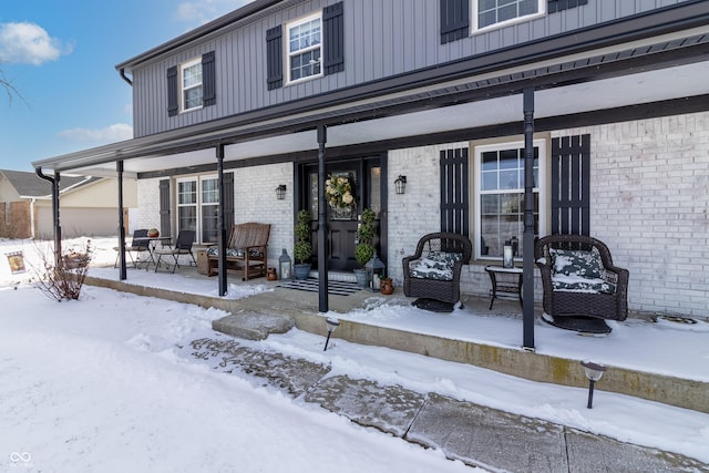 snow covered property entrance with board and batten siding and brick siding