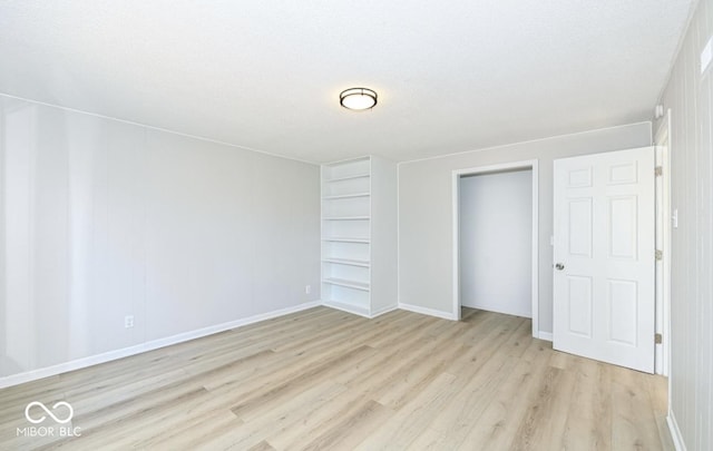 unfurnished bedroom with a closet, baseboards, a textured ceiling, and light wood finished floors