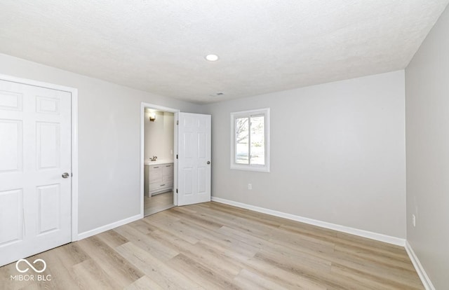 unfurnished bedroom with light wood-style floors, baseboards, and a textured ceiling