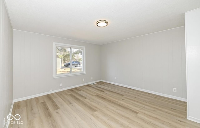 empty room featuring light wood-type flooring, visible vents, and baseboards