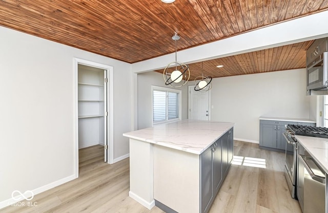 kitchen featuring a kitchen island, hanging light fixtures, appliances with stainless steel finishes, gray cabinets, and light stone countertops