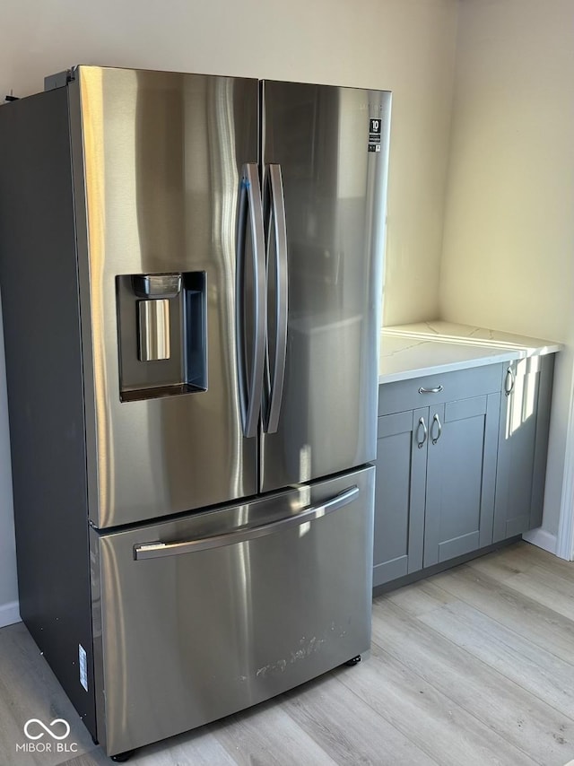 kitchen with gray cabinetry, light wood finished floors, and stainless steel fridge with ice dispenser