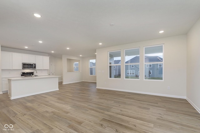 unfurnished living room with baseboards, light wood finished floors, and recessed lighting