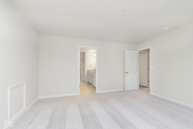 unfurnished bedroom with light carpet, connected bathroom, and baseboards