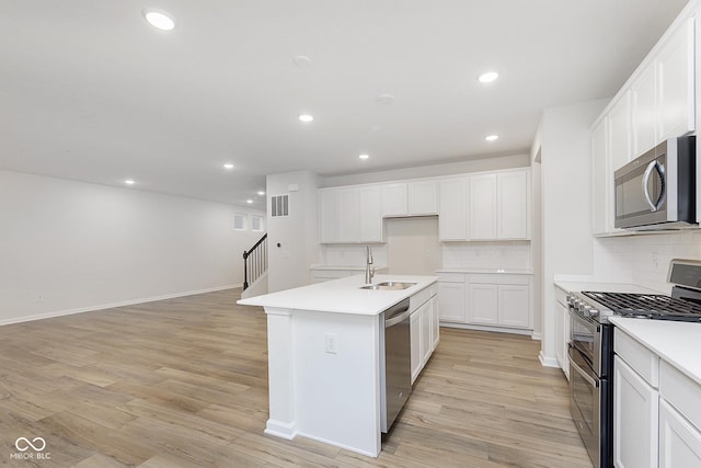 kitchen featuring a sink, white cabinets, light countertops, appliances with stainless steel finishes, and a center island with sink