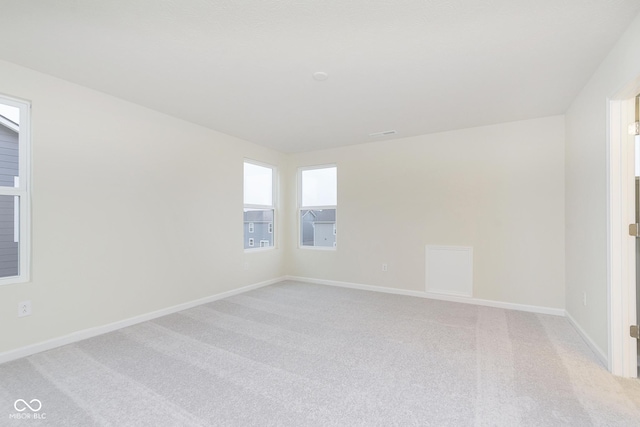 spare room featuring light carpet and baseboards