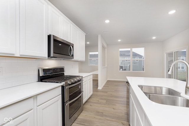 kitchen with white cabinets, appliances with stainless steel finishes, light countertops, and a sink