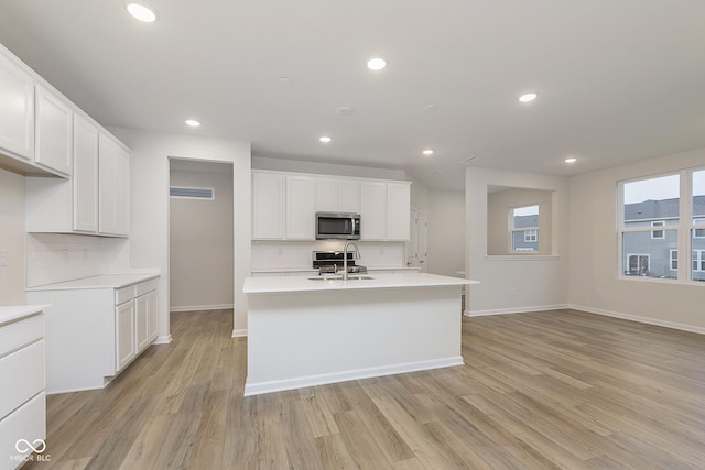 kitchen featuring stainless steel appliances, light countertops, decorative backsplash, white cabinets, and a sink