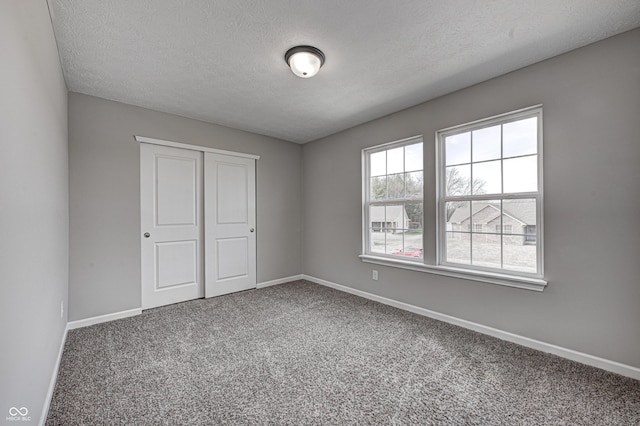 unfurnished bedroom featuring a closet, a textured ceiling, and carpet flooring