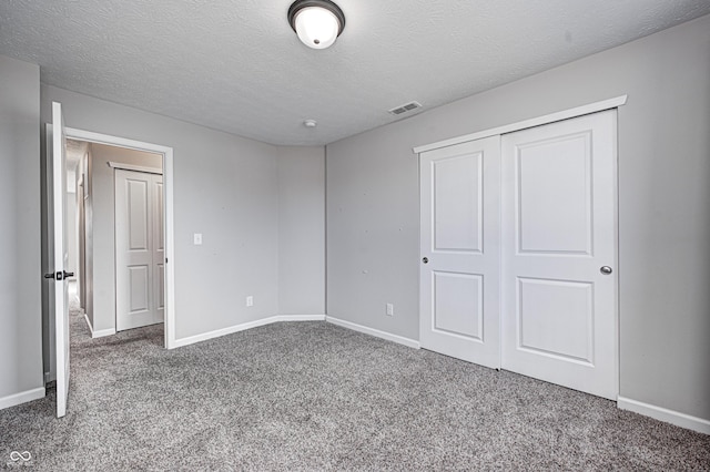 unfurnished bedroom with carpet floors, a closet, and a textured ceiling