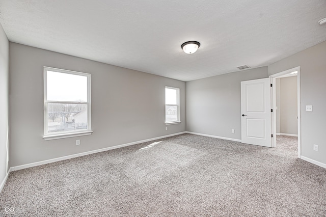 carpeted empty room featuring a textured ceiling