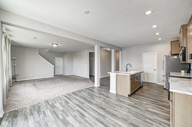 kitchen with sink, light hardwood / wood-style floors, an island with sink, and appliances with stainless steel finishes