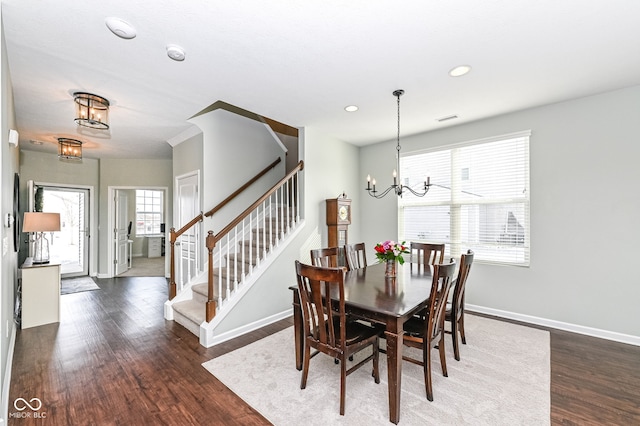 dining area featuring dark wood-type flooring, visible vents, baseboards, stairs, and an inviting chandelier