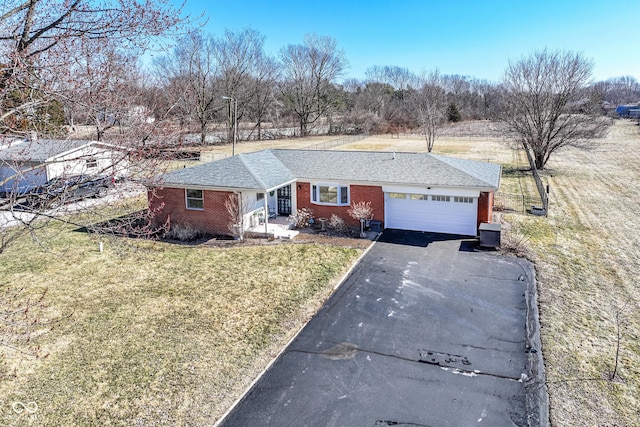 ranch-style house with brick siding, central AC, a garage, driveway, and a front lawn