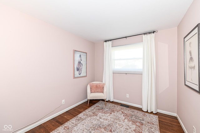 sitting room with dark wood-style flooring, visible vents, and baseboards