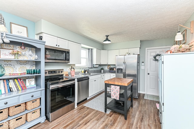 kitchen featuring appliances with stainless steel finishes, wood counters, white cabinetry, and light wood-style floors