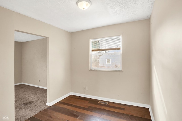 empty room with dark hardwood / wood-style flooring and a textured ceiling