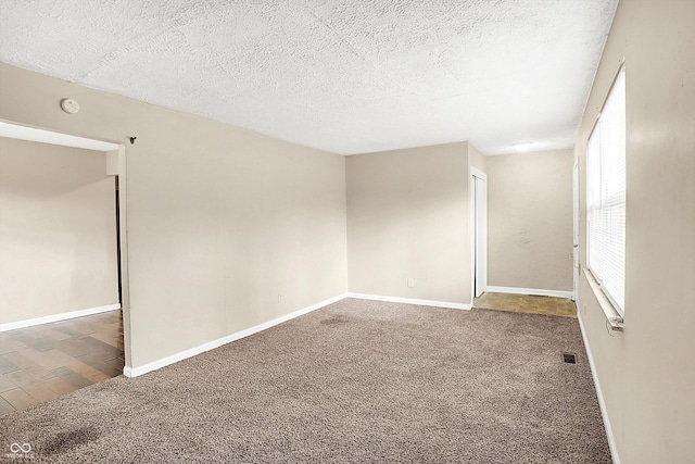 carpeted empty room featuring a textured ceiling