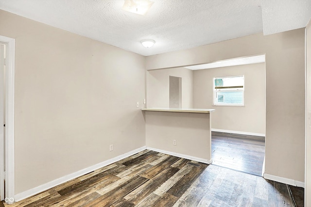 empty room with dark hardwood / wood-style floors and a textured ceiling