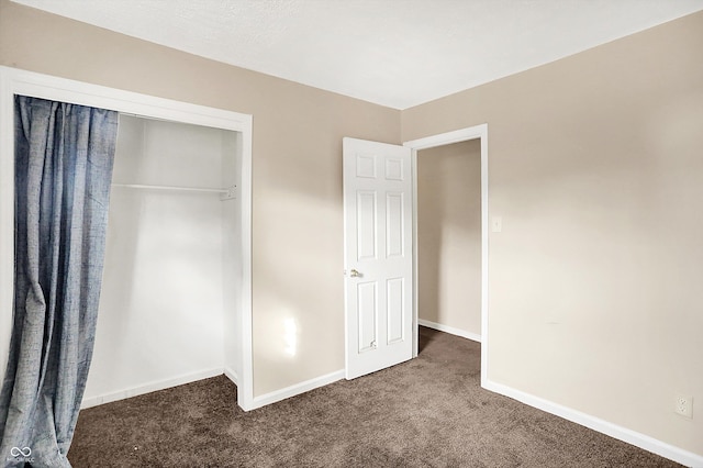 unfurnished bedroom featuring dark carpet and a closet