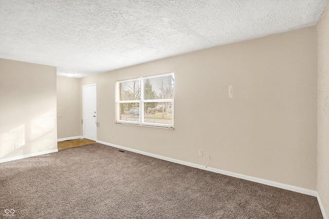 unfurnished room with carpet flooring and a textured ceiling