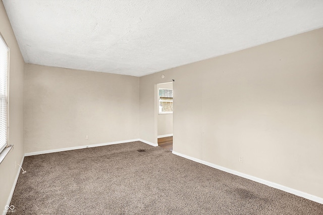 spare room featuring a textured ceiling and dark carpet