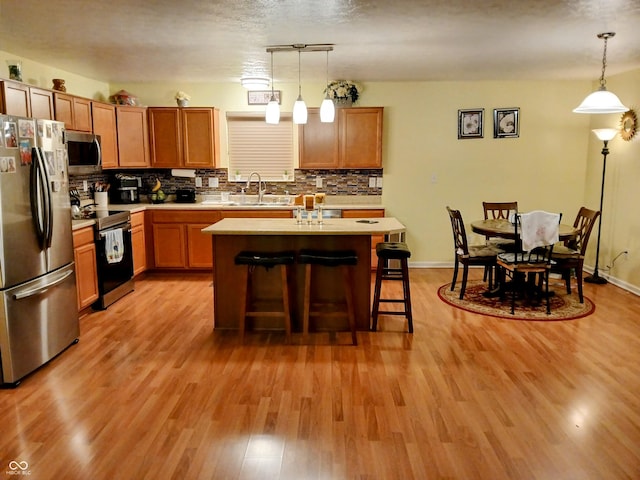 kitchen featuring a kitchen island, appliances with stainless steel finishes, sink, and pendant lighting