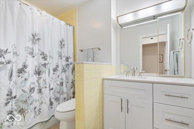 bathroom featuring tile walls, vanity, toilet, and a shower with shower curtain