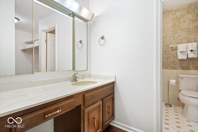 bathroom featuring vanity, tile walls, and toilet