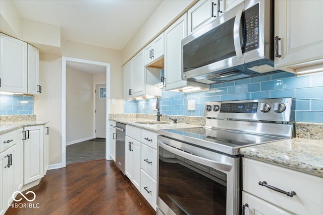 kitchen with appliances with stainless steel finishes, tasteful backsplash, white cabinetry, sink, and light stone counters