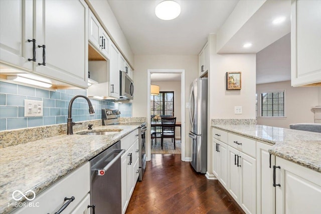 kitchen featuring sink, white cabinetry, tasteful backsplash, stainless steel appliances, and light stone countertops