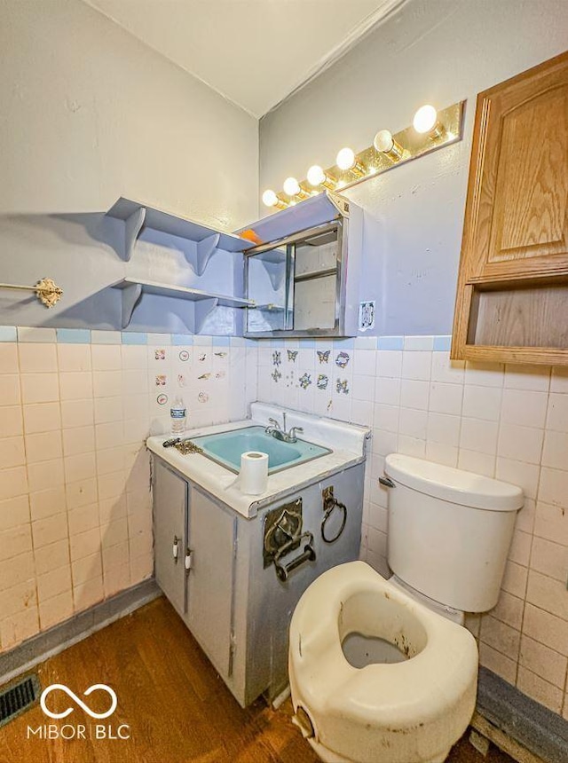 bathroom featuring hardwood / wood-style floors, toilet, sink, and tile walls