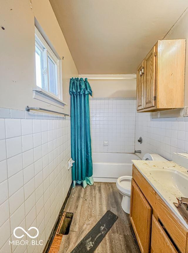 full bathroom with tile walls, hardwood / wood-style flooring, vanity, toilet, and shower / bathtub combination with curtain