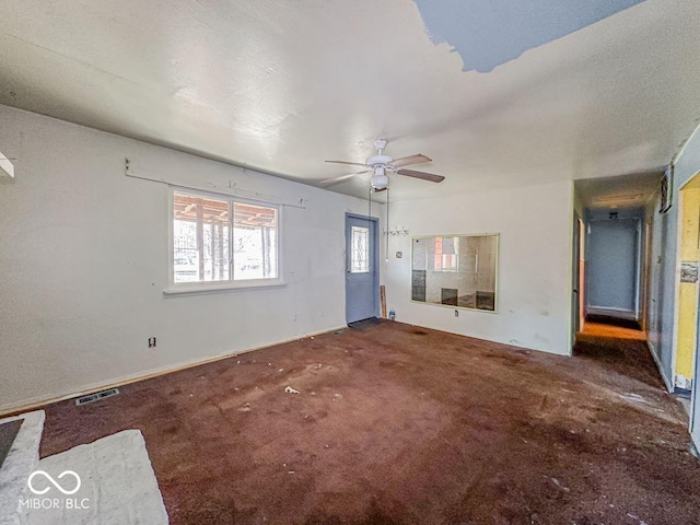 unfurnished living room with ceiling fan and dark colored carpet