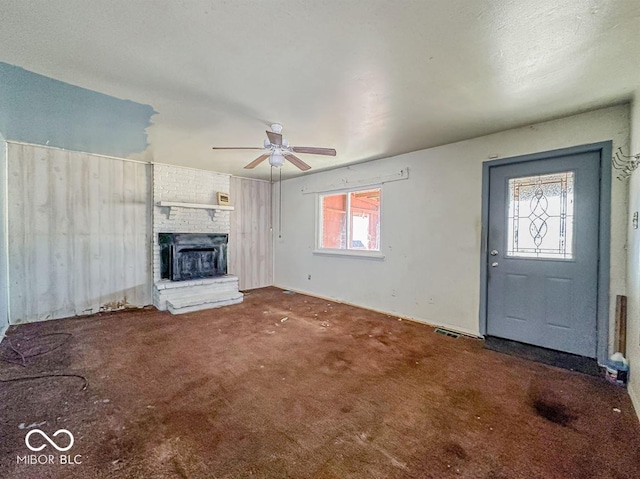 unfurnished living room with ceiling fan, carpet, and a fireplace