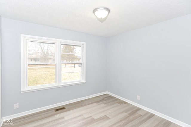 empty room featuring light hardwood / wood-style floors and a textured ceiling