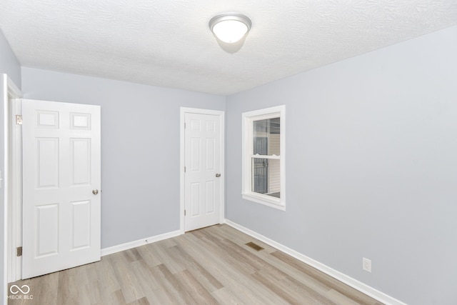 empty room with light hardwood / wood-style floors and a textured ceiling