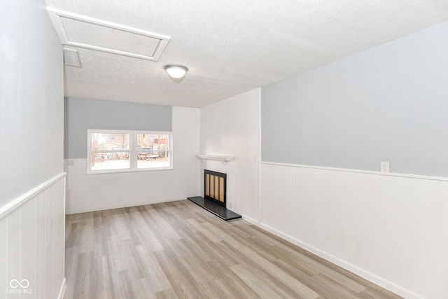 unfurnished living room featuring a textured ceiling and light hardwood / wood-style floors