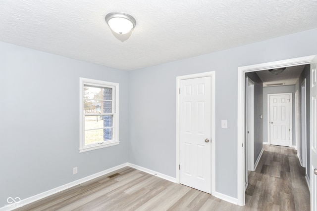 spare room featuring hardwood / wood-style floors and a textured ceiling