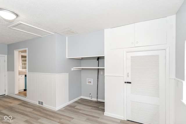 clothes washing area with hookup for a washing machine, light hardwood / wood-style flooring, and a textured ceiling