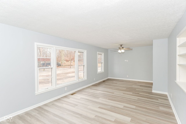 unfurnished room with a textured ceiling and light wood-type flooring