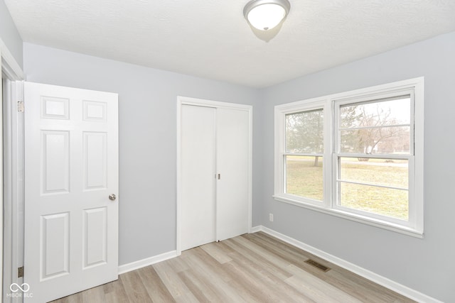 unfurnished bedroom featuring light hardwood / wood-style floors, a closet, and a textured ceiling