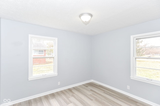 unfurnished room with plenty of natural light, light hardwood / wood-style flooring, and a textured ceiling