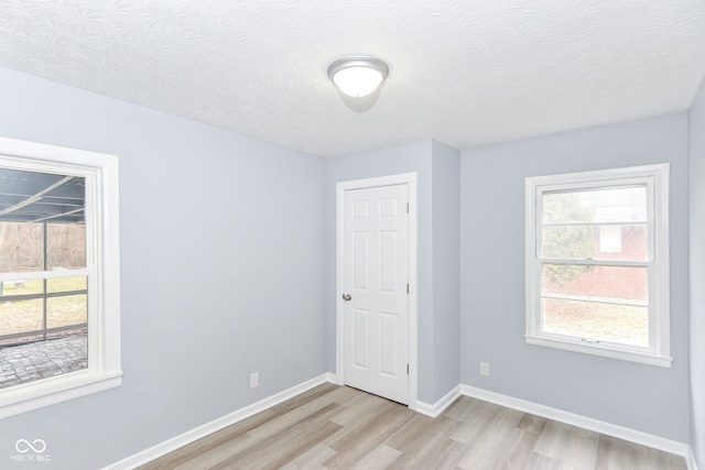 unfurnished room featuring a textured ceiling and light hardwood / wood-style floors