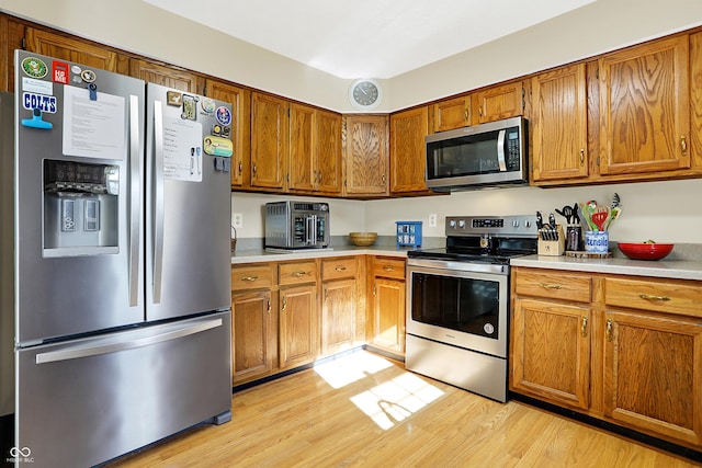 kitchen with appliances with stainless steel finishes and light hardwood / wood-style flooring