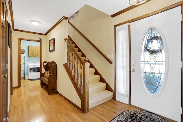 entryway featuring ornamental molding, washer / dryer, and light hardwood / wood-style floors