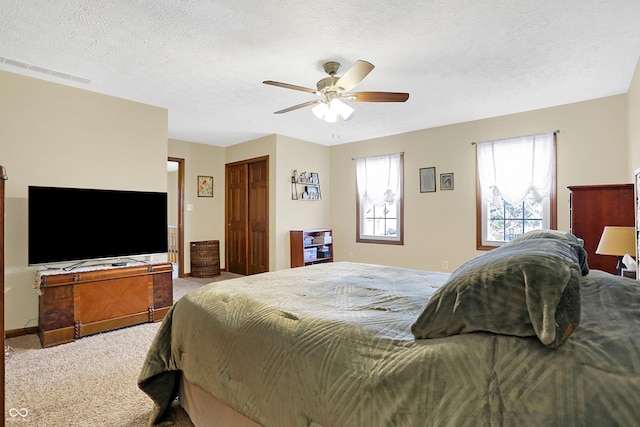 bedroom with multiple windows, ceiling fan, a textured ceiling, and carpet