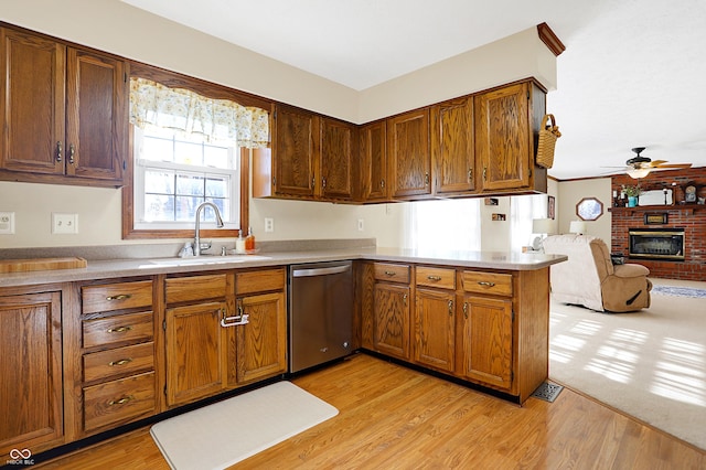 kitchen featuring sink, stainless steel dishwasher, kitchen peninsula, and light wood-type flooring